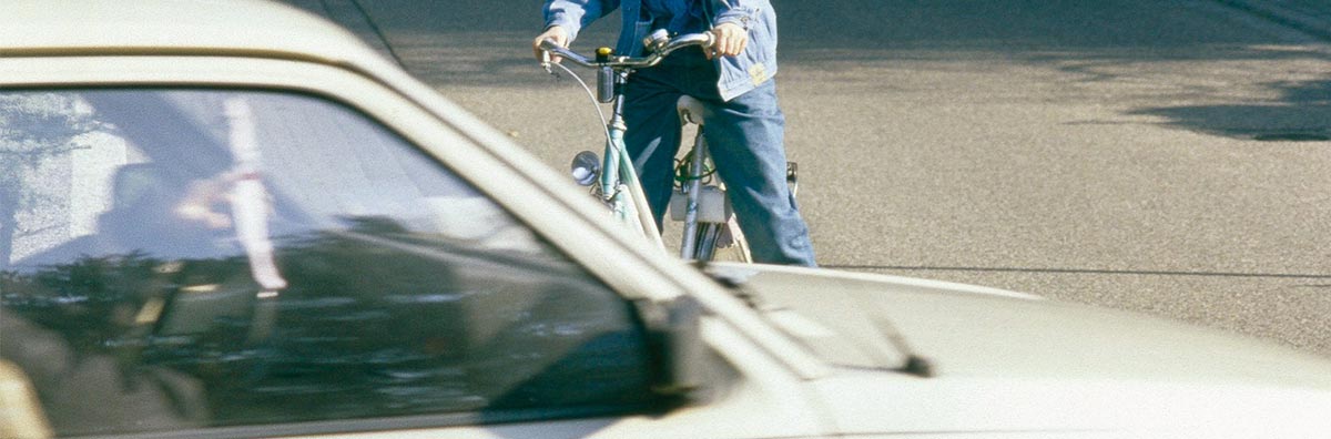 歩道で待機する自転車と横断する自動車